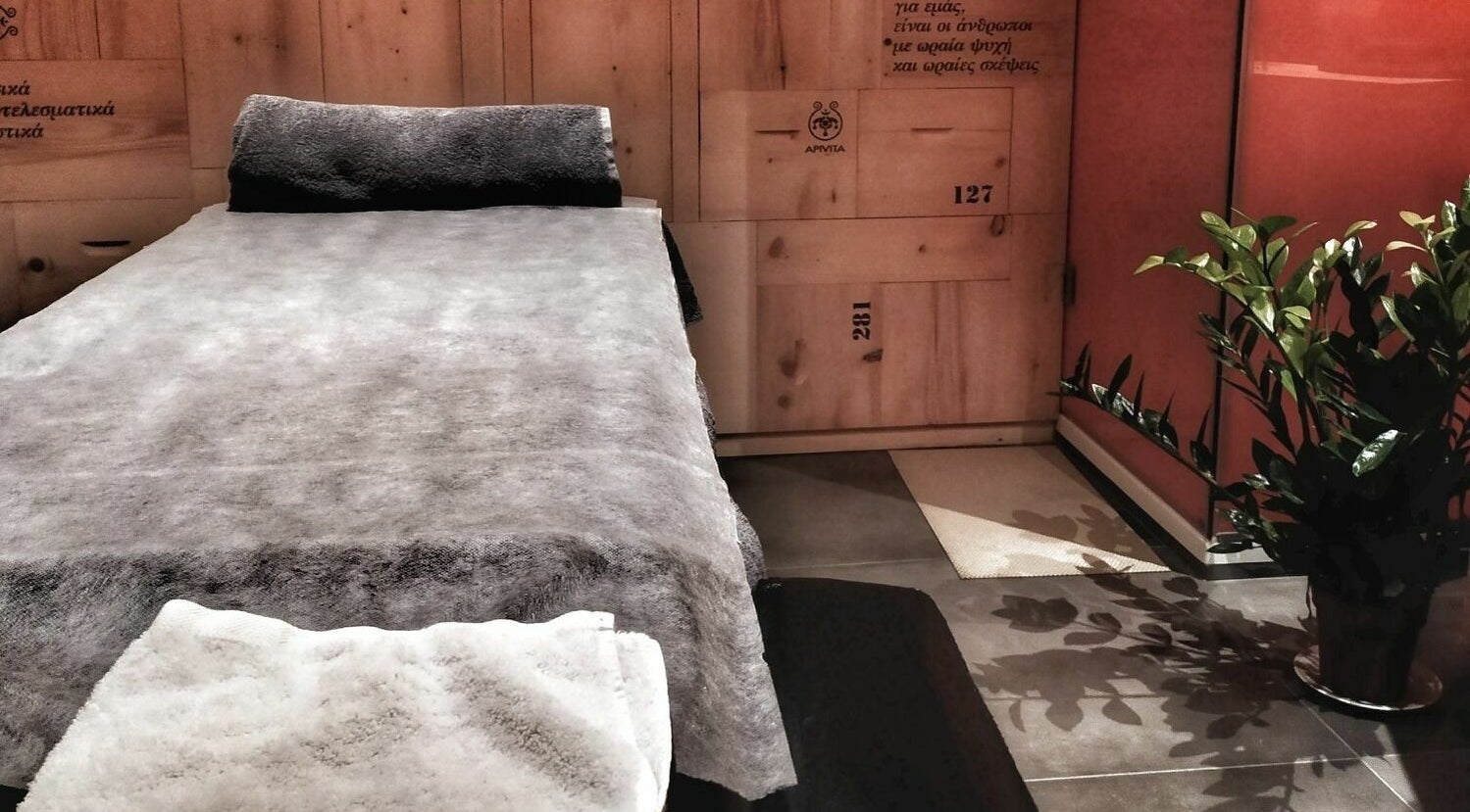 Χαλαρωτικός χώρος μασάζ στο Apotheke Spa, Χανιά, GR με πράσινο φυτό και απαλό φωτισμό.