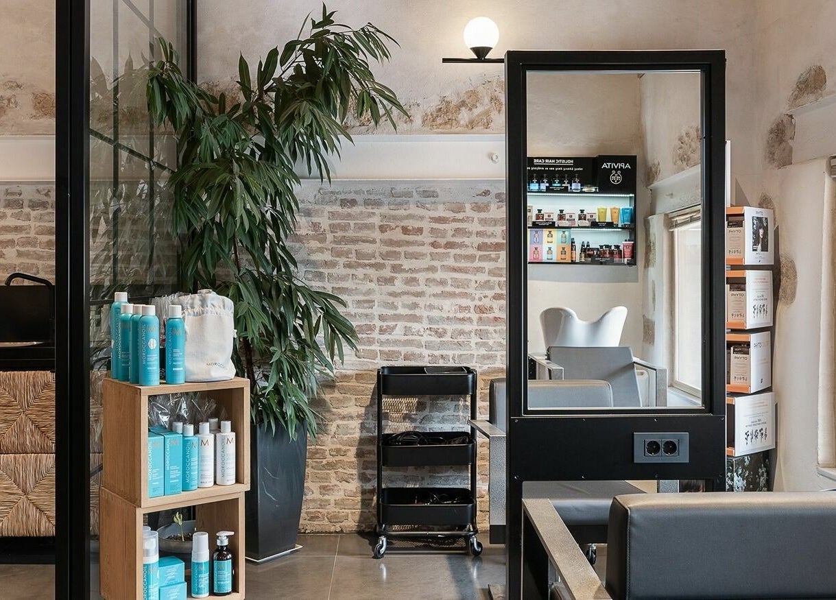 Κομψός χώρος περιποίησης στο Apotheke Spa, Χανιά, GR με φόντο τούβλα και προϊόντα ομορφιάς.