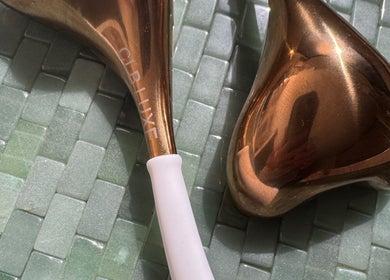 Bronze Gua Sha tool on a green tile at Soulful Skin Studio, Sydney, New South Wales, AU.