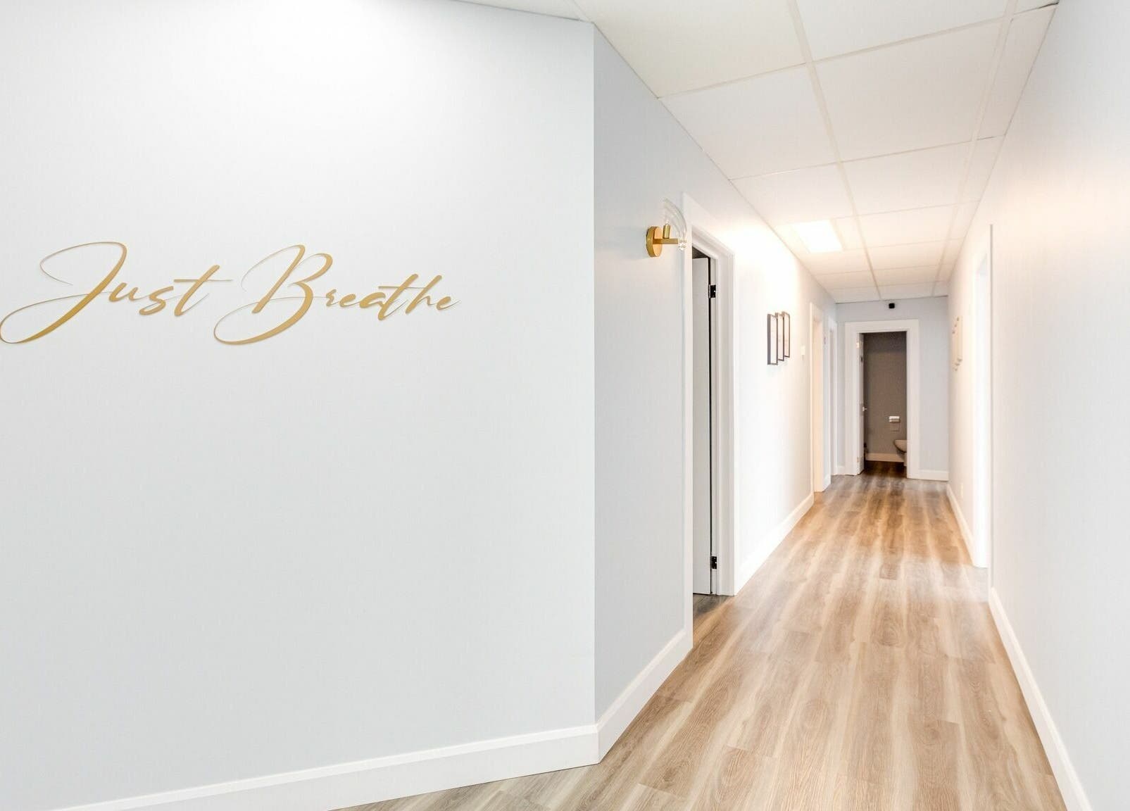Bright hallway with 'Just Breathe' wall art at Wellness Center Massotherapie Sandra, Laval, Québec, CA.