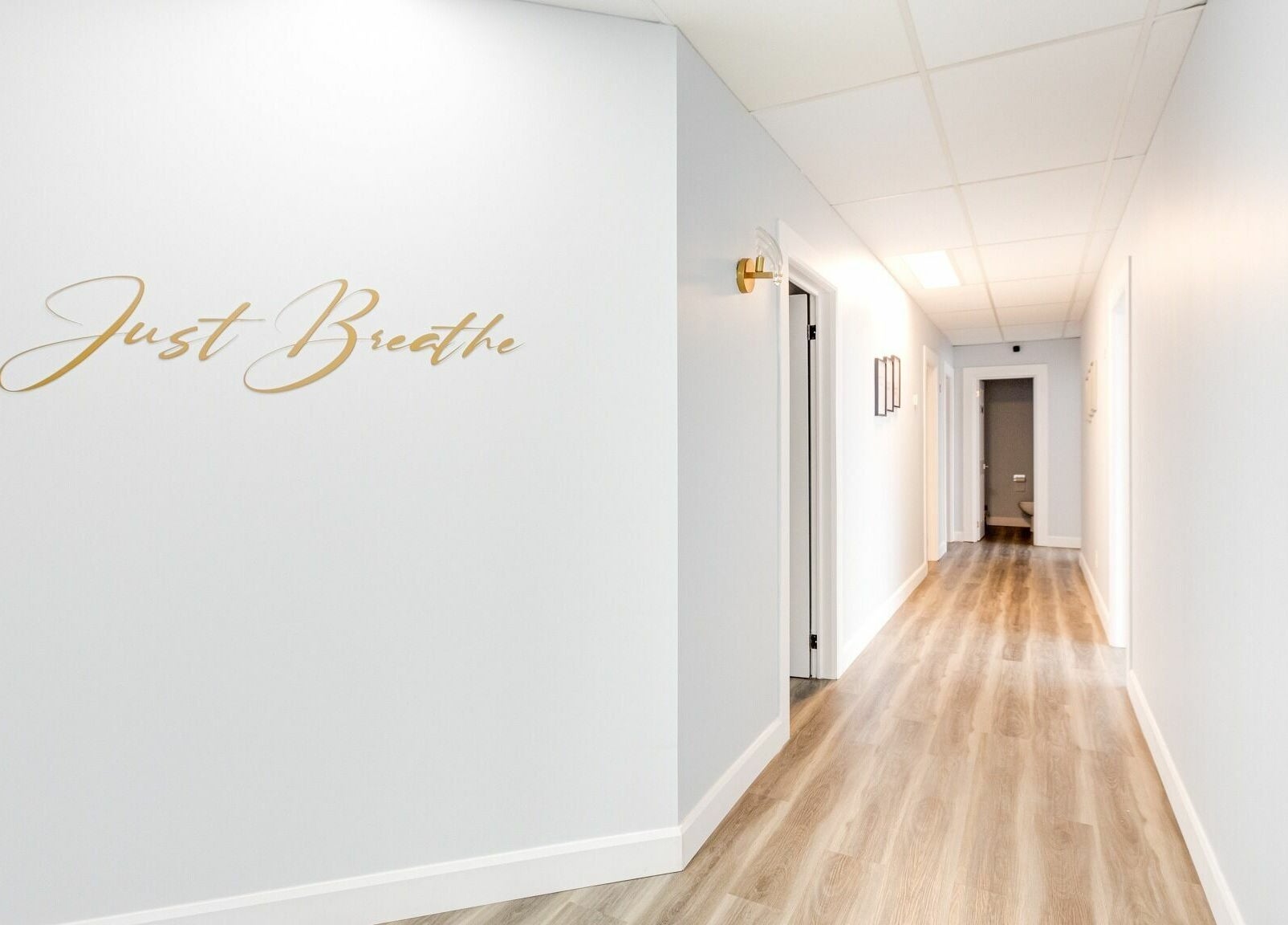 Bright hallway with 'Just Breathe' wall art at Wellness Center Massotherapie Sandra, Laval, Québec, CA.