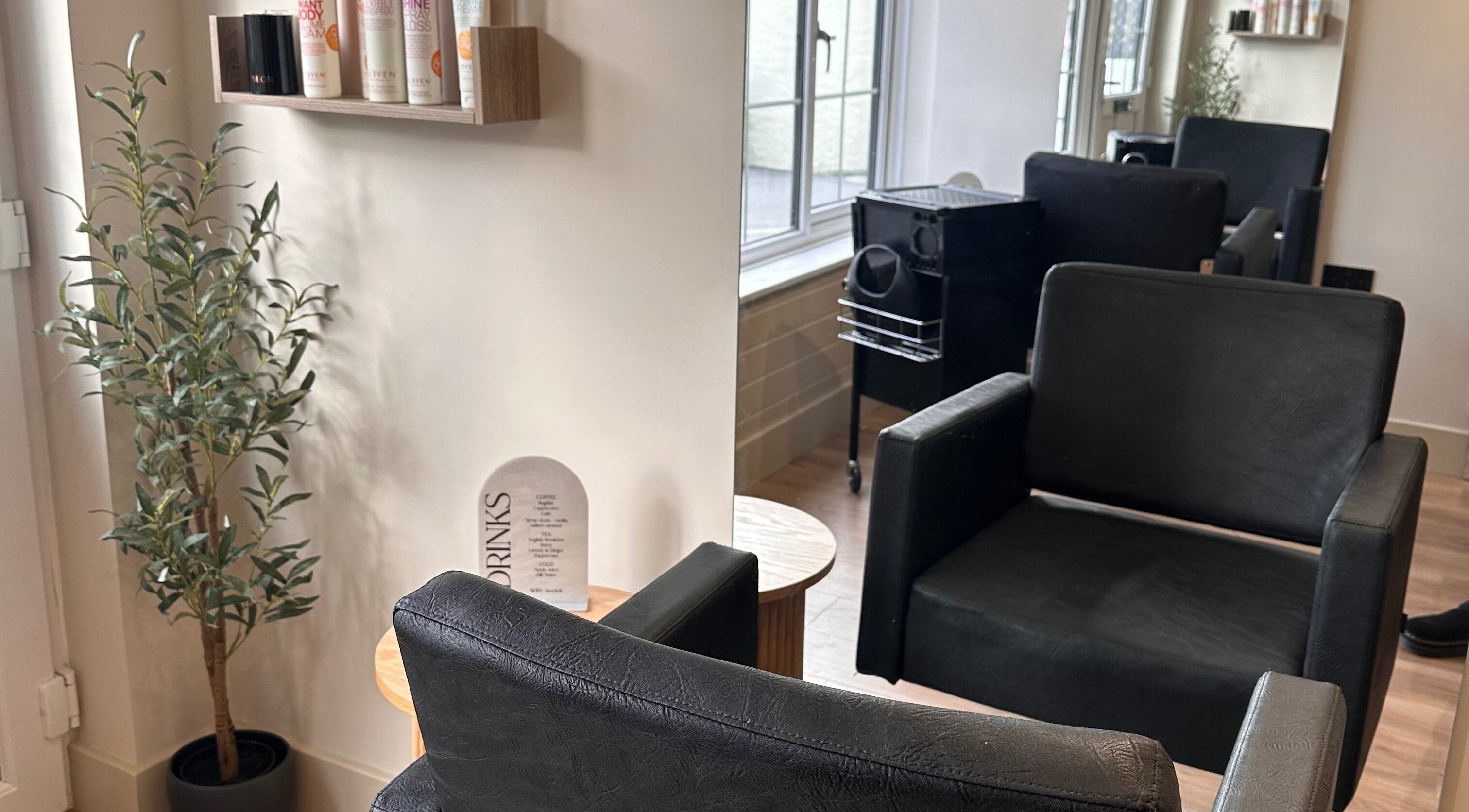 Chic salon seating at Nine Hair Lounge, Saint Newlyn East, England, GB with sleek chairs and product display.