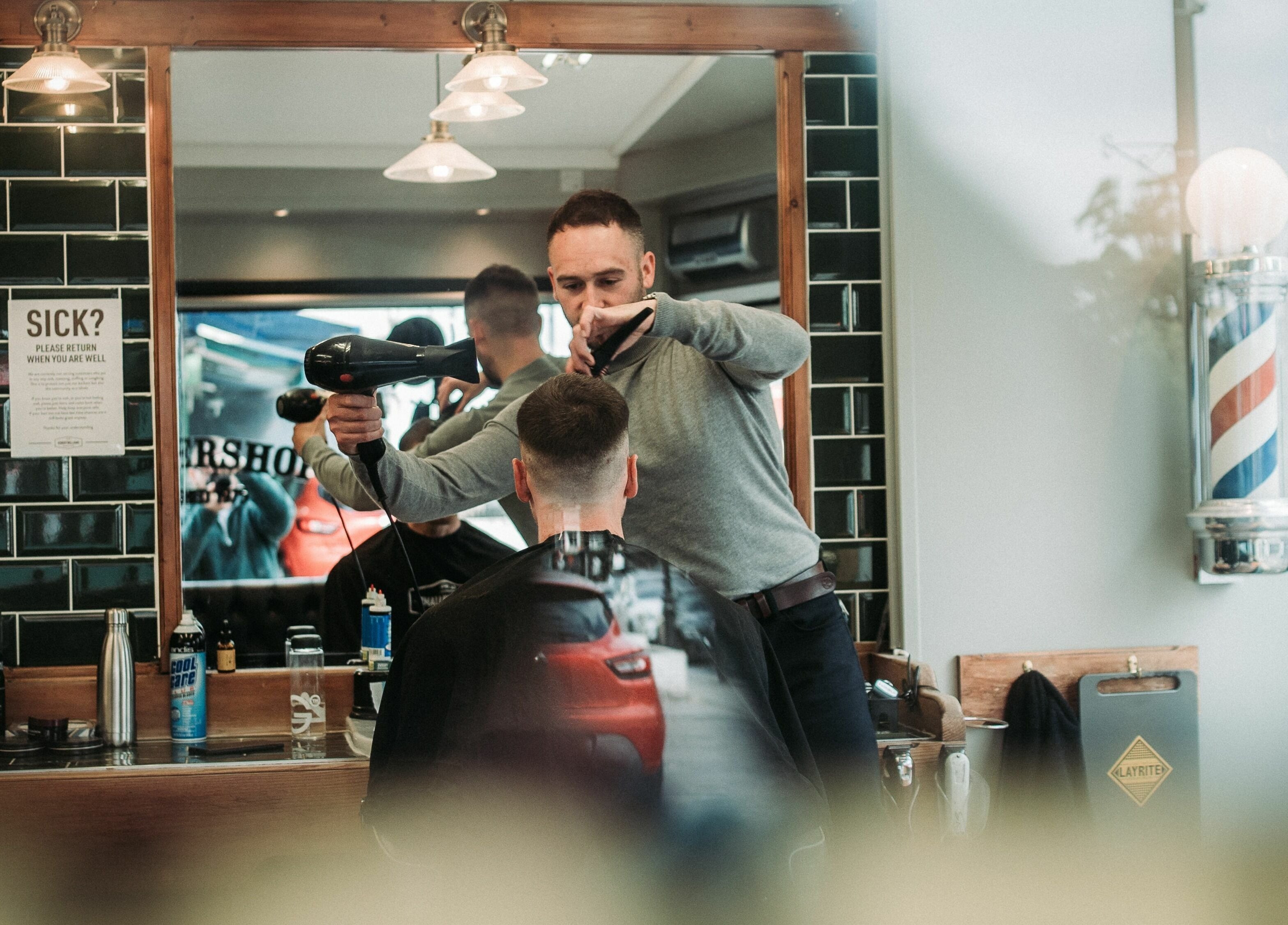 Stylist at Robert Williams Barbershop in Southend-on-Sea, England, GB perfecting a haircut with a hairdryer.