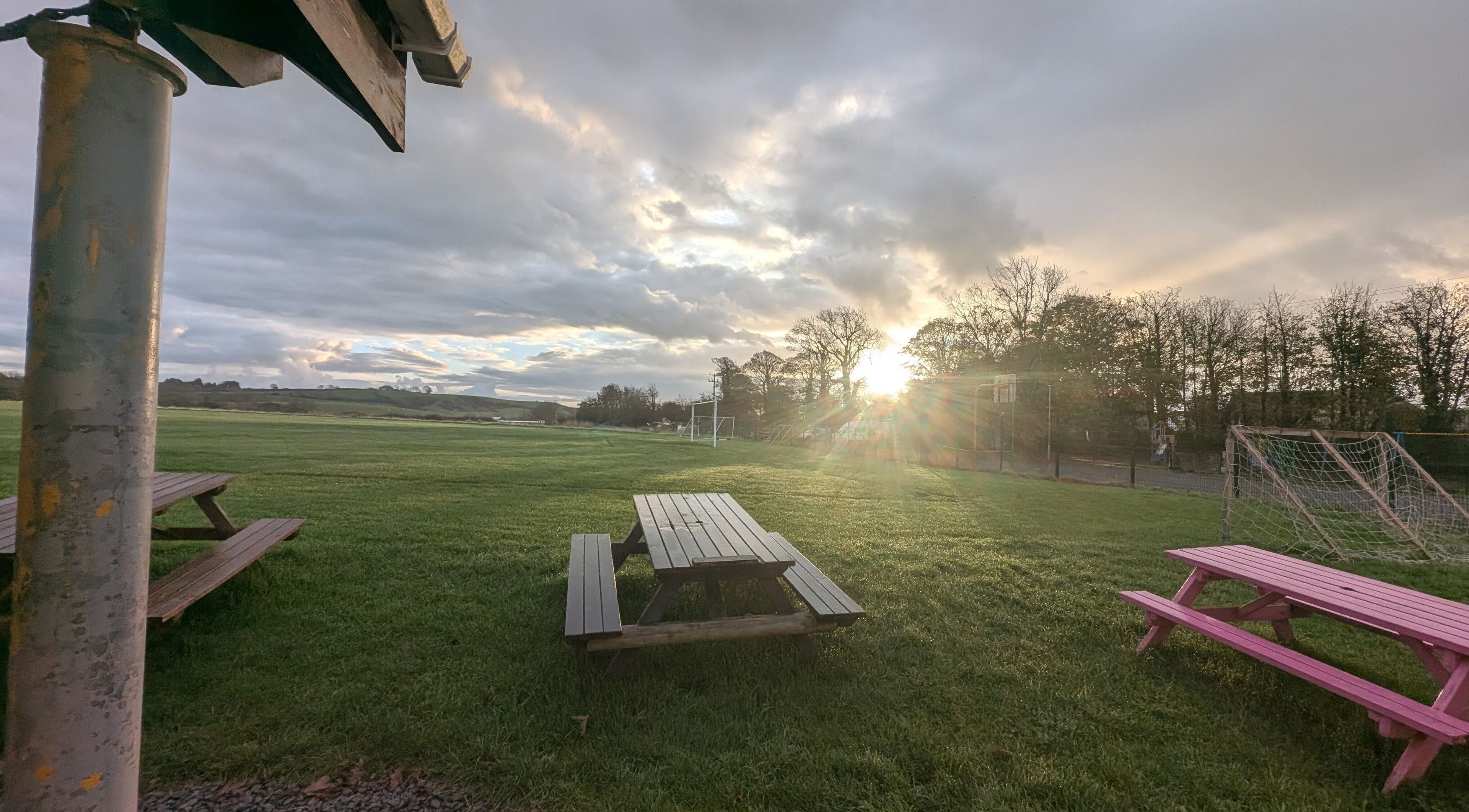 Sunset over picnic benches at Kerrie’s PMA Fitness, Tenby, Wales, GB. Scenic outdoor space with lush greenery.