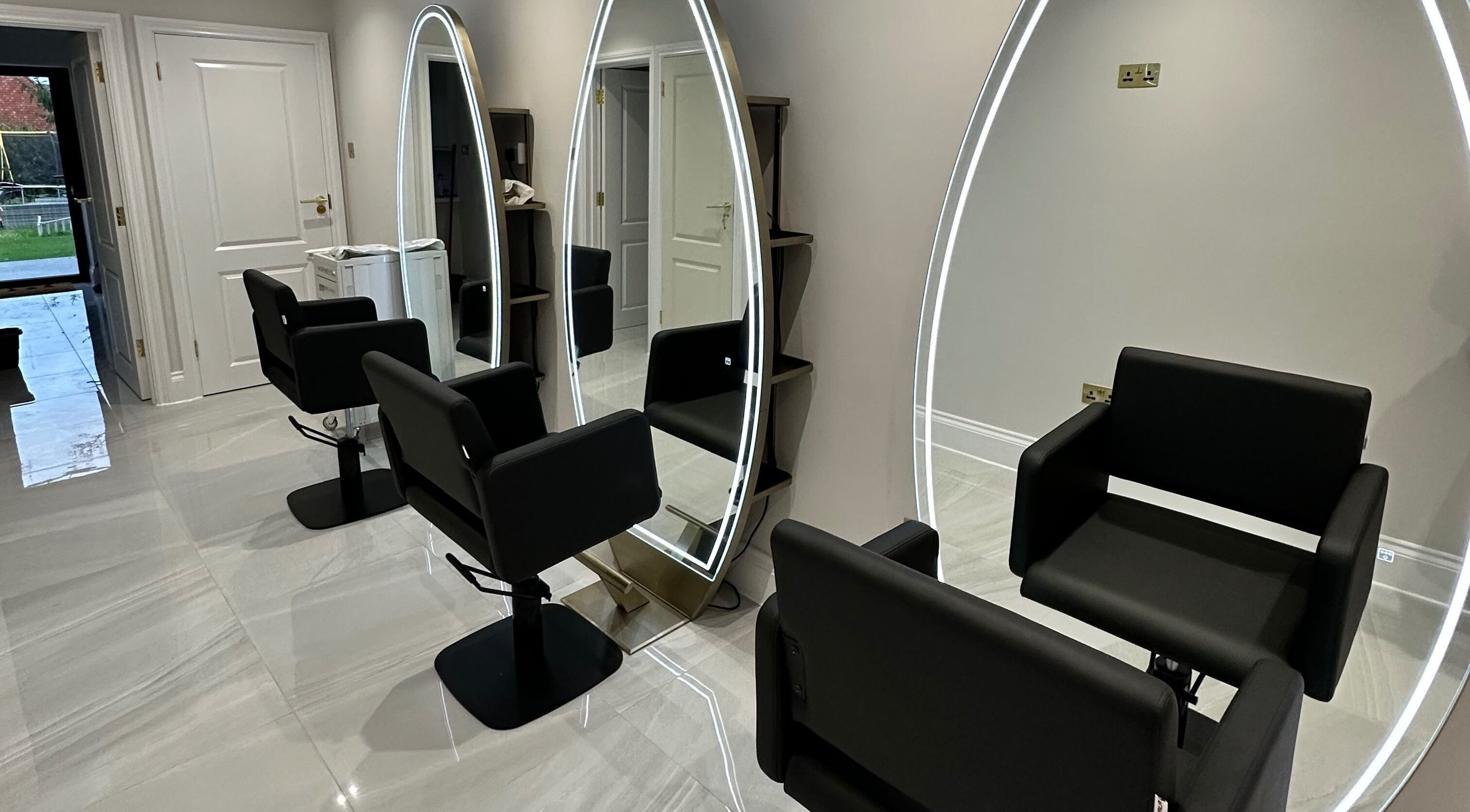Elegant salon chairs and illuminated mirrors at Hair Fairy, Billericay, England, GB.