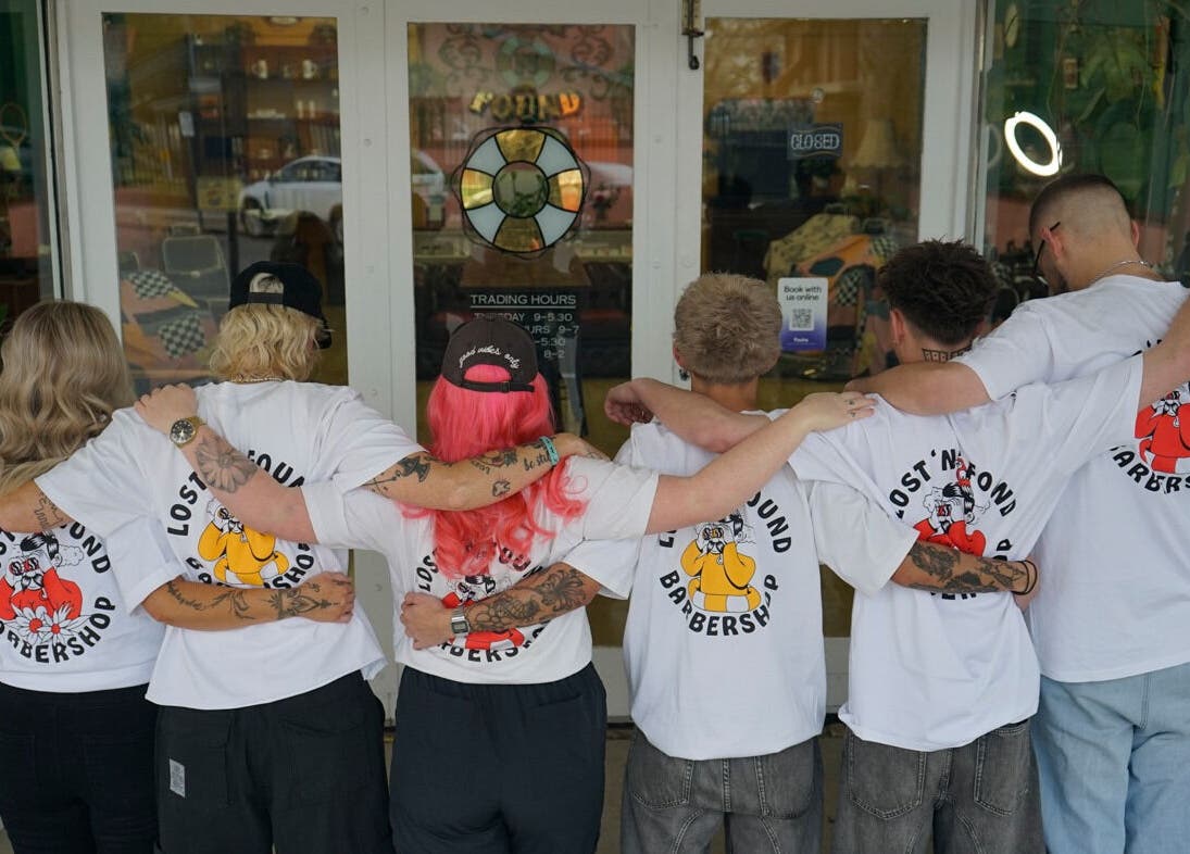 Team members with linked arms outside Lost N Found Barbers, Albury, New South Wales, AU.