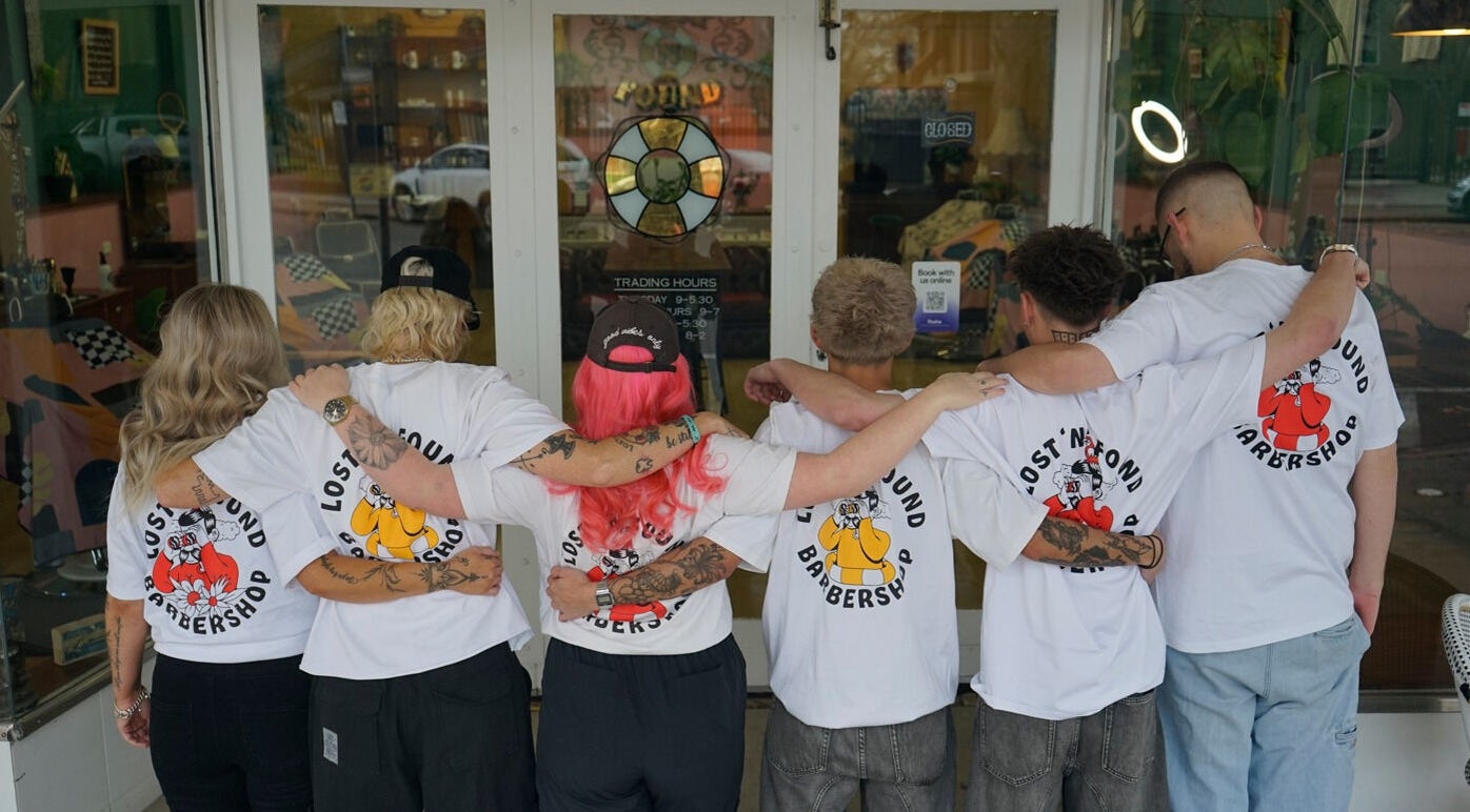 Team members with linked arms outside Lost N Found Barbers, Albury, New South Wales, AU.