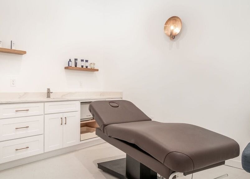 Relaxing treatment room at Merum Face Bar in Allen, Texas, US with a modern spa bed and minimalist decor.