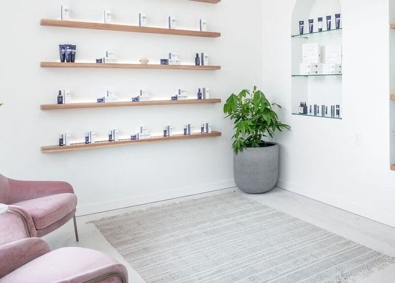 Peaceful interior of Merum Face Bar in Allen, Texas, US with pink chairs and product shelves.