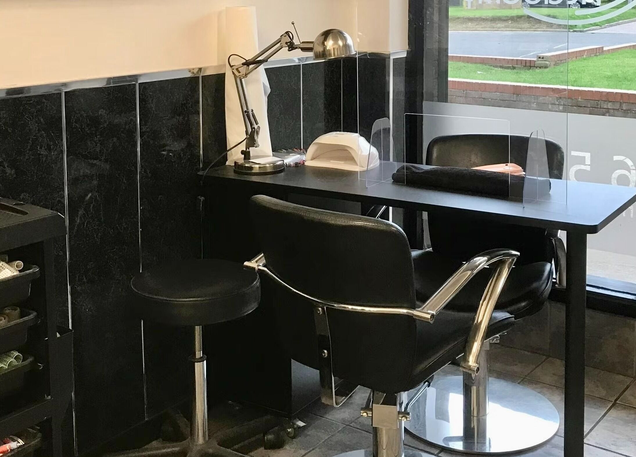 Modern nail station at Hair and Body in Colchester, England, GB, featuring sleek black chairs and manicure tools.