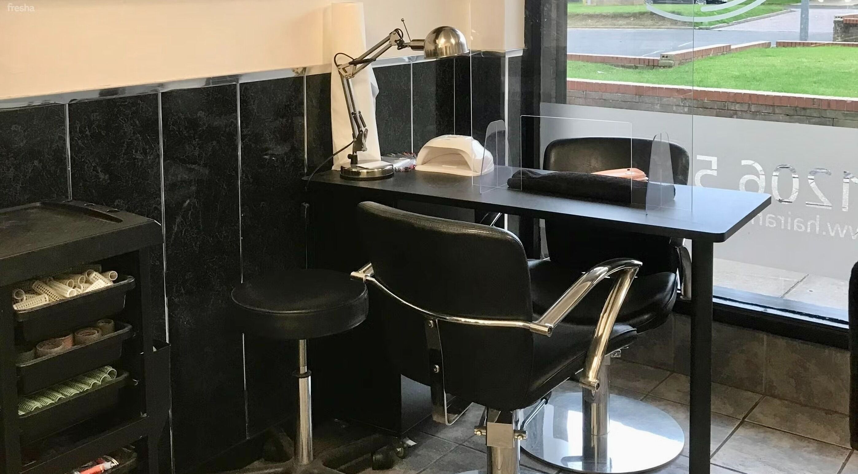 Modern nail station at Hair and Body in Colchester, England, GB, featuring sleek black chairs and manicure tools.