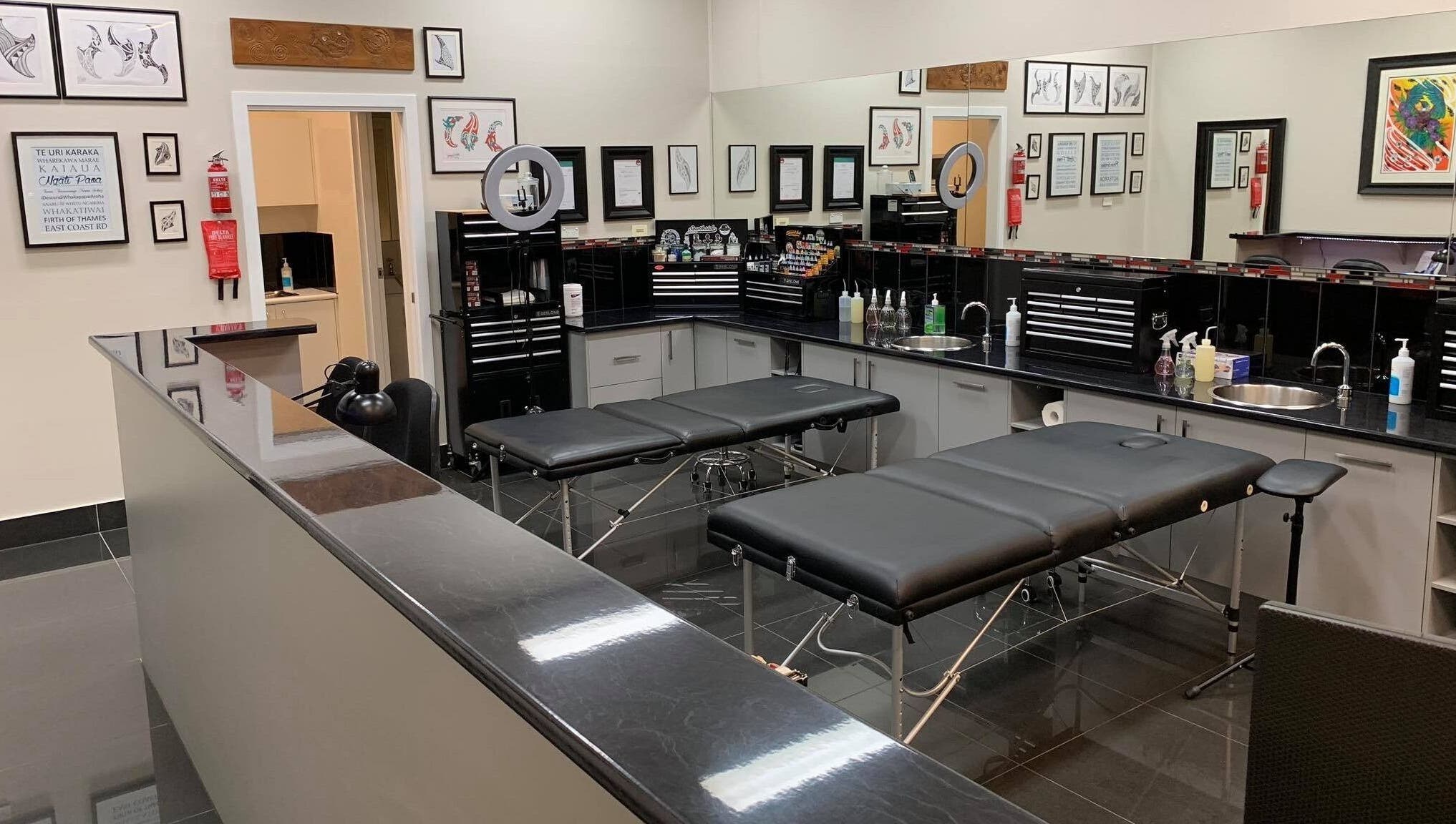 Modern tattoo studio setup at Tatauarangi Ink in Helensvale, Queensland, AU. Clean black benches and art on walls.