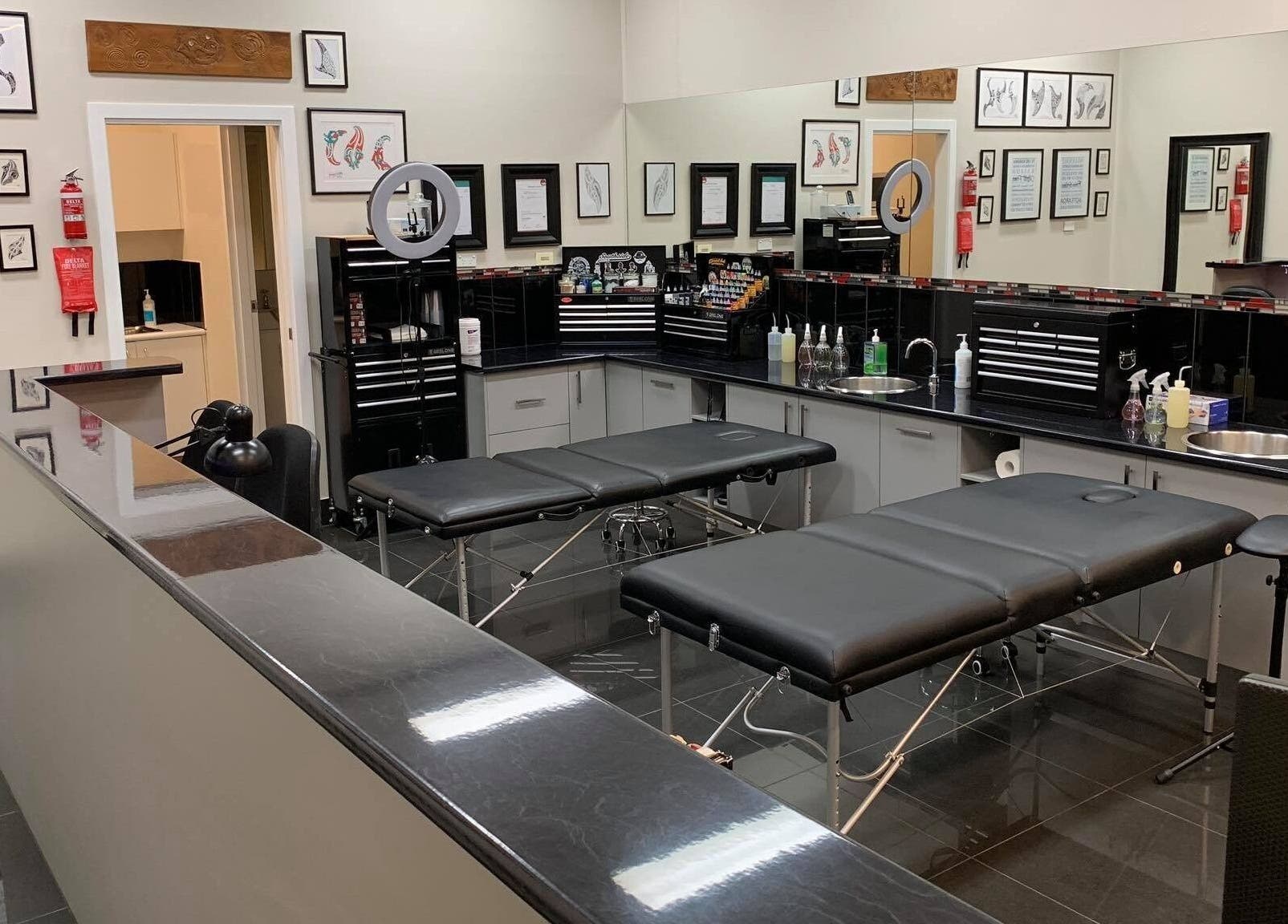 Modern tattoo studio setup at Tatauarangi Ink in Helensvale, Queensland, AU. Clean black benches and art on walls.