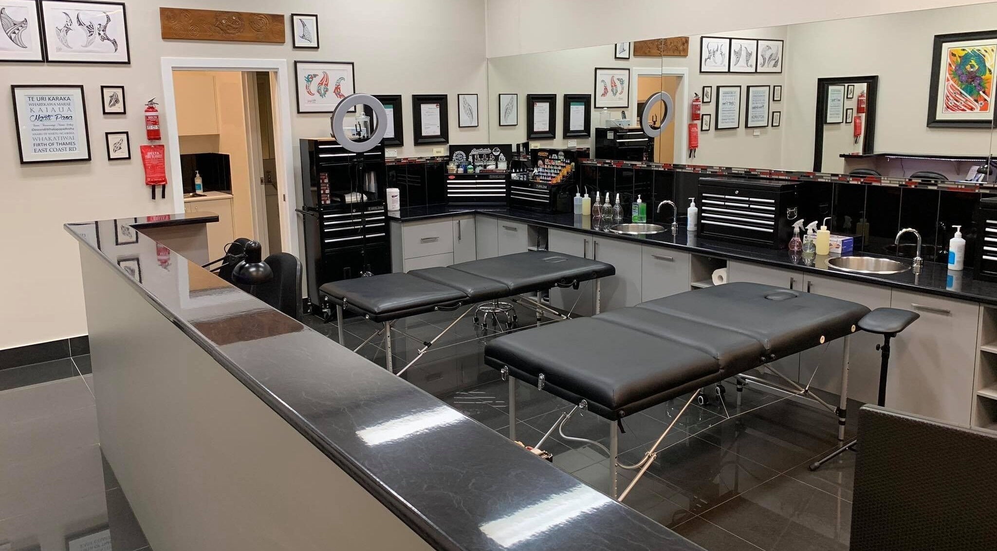 Modern tattoo studio setup at Tatauarangi Ink in Helensvale, Queensland, AU. Clean black benches and art on walls.