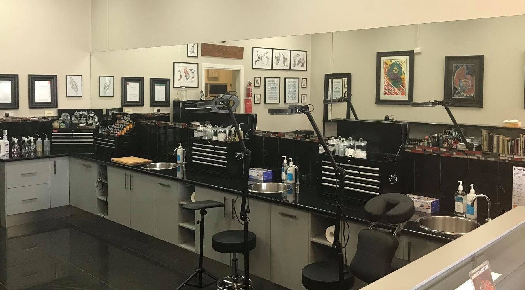 Professional tattoo studio setup at Tatauarangi Ink, Helensvale, Queensland, AU with tools and art displays.