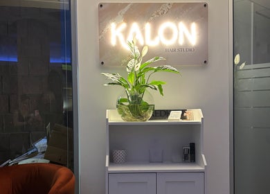 Elegant entryway at Kalon Hair Studio, Edinburgh, Scotland, GB with glowing sign and plant decor.