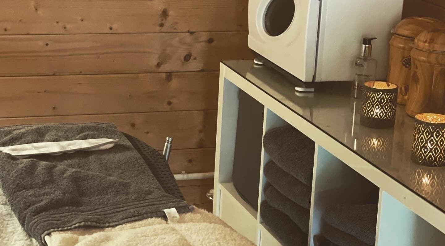 Cozy treatment room at Hygge Beauty Room in West Molesey, England, GB, with warm wooden decor and soft linens.