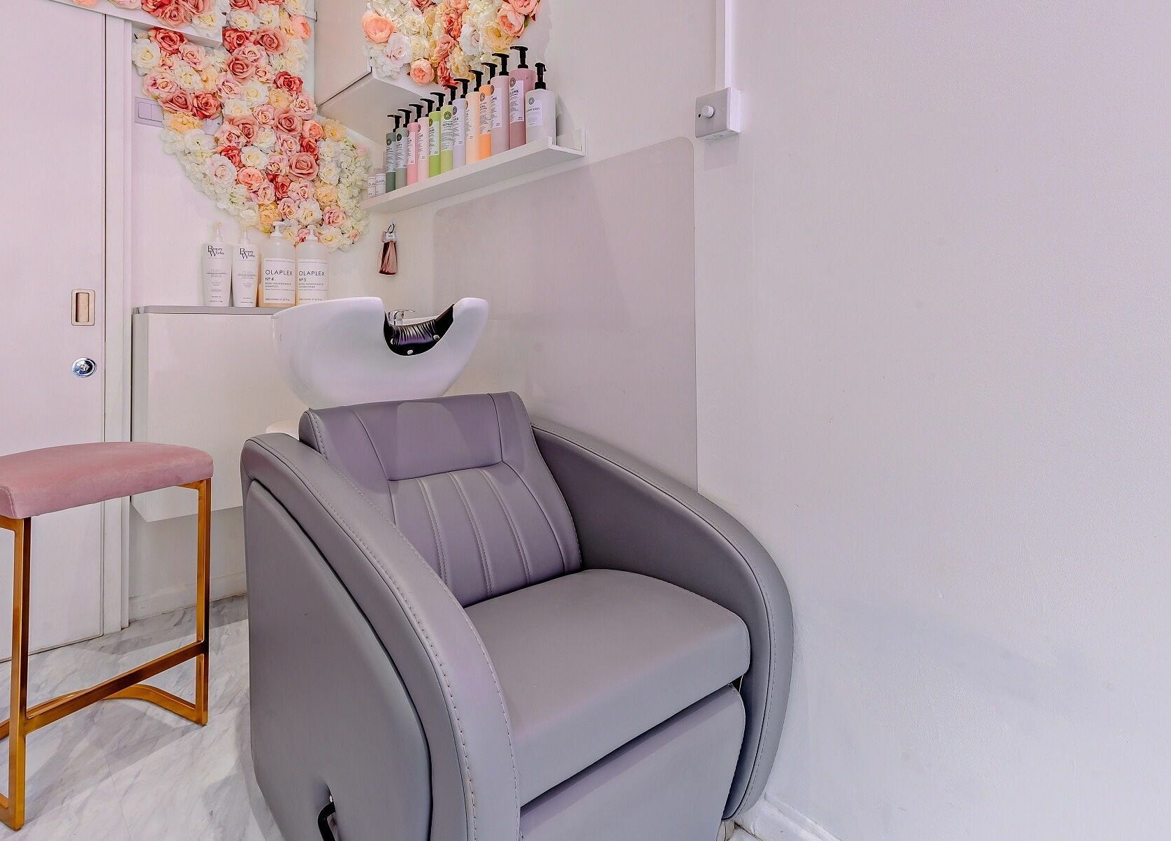 Elegant salon hair wash station with plush chair at AKai, London, England, GB, adorned with floral decor.