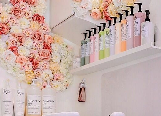 AKai salon in London, England with floral wall and shelves of beauty products.