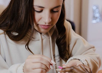 Manicurist at Fix Her Crown in Benoni, Gauteng, ZA expertly painting nails with pink polish.