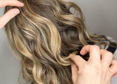 Stylist adjusts wavy blonde hair at Liam Dawson Hair, Ashford, England, GB.