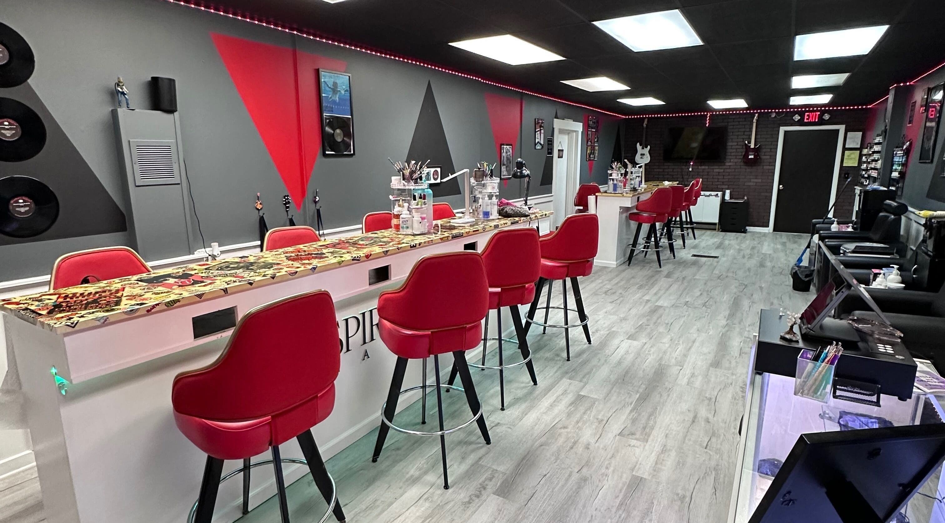 Modern interior of Inspired Designs Nail Bar in Massillon, Ohio, US, featuring stylish red chairs and decor.