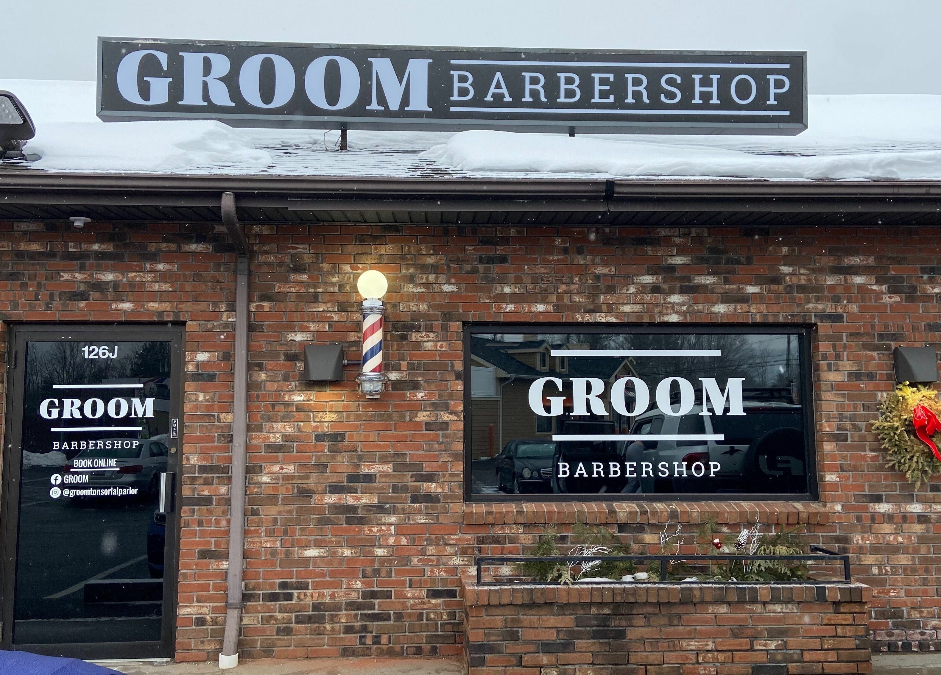 Exterior of Groom Barbershop, Easthampton, Massachusetts, US, showcasing its inviting entrance and brick facade.
