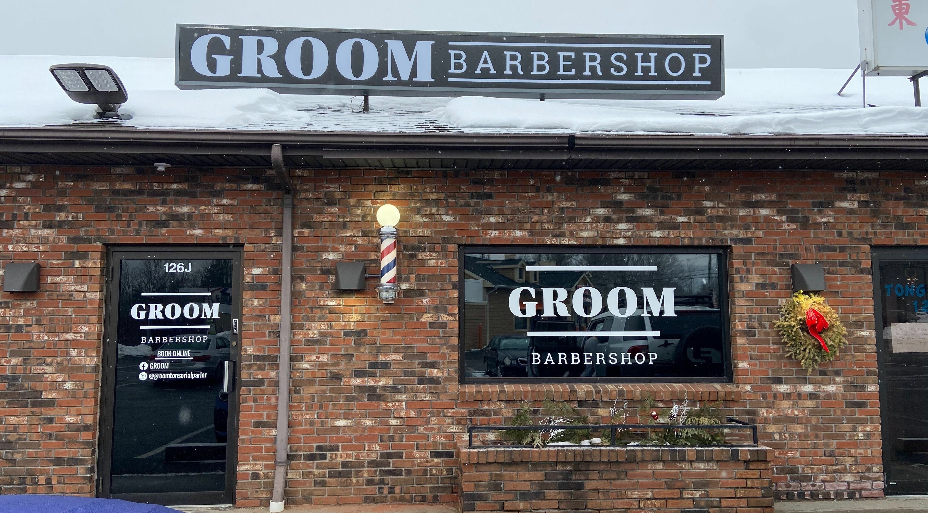 Exterior of Groom Barbershop, Easthampton, Massachusetts, US, showcasing its inviting entrance and brick facade.