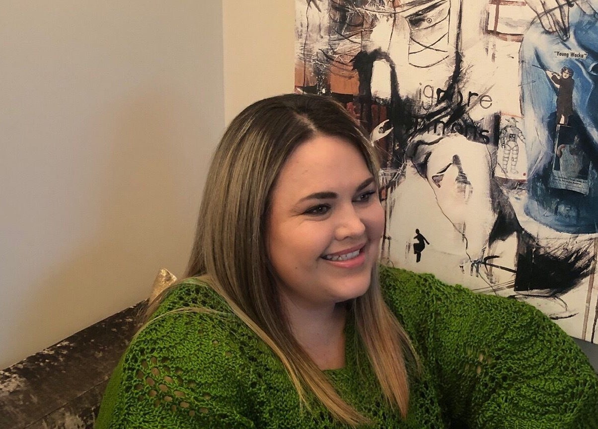 Woman smiling at Floresence Nail Studio, Masterton, Wellington Region, NZ, near an artistic wall painting.