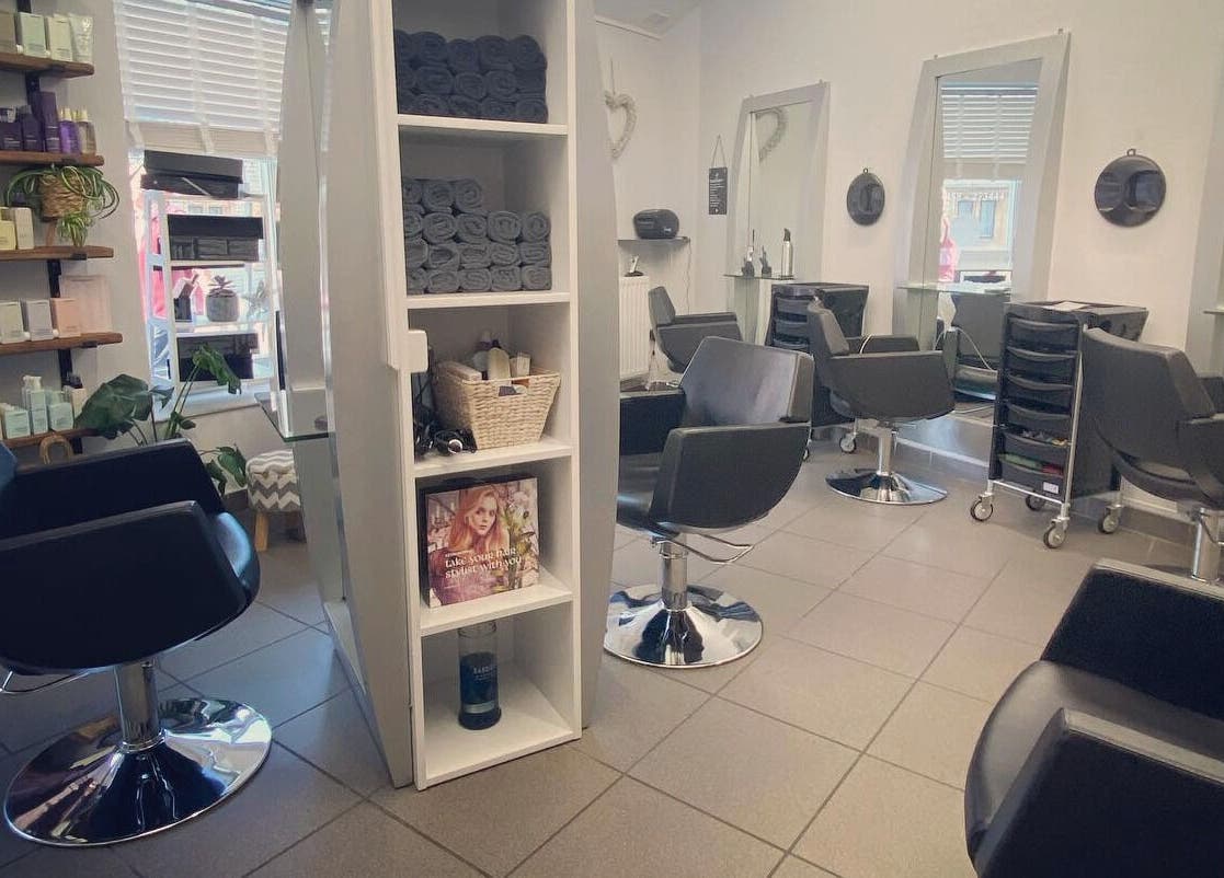 Elegant salon interior at House of Hair, Somerton, England, GB, featuring modern chairs and styling products.