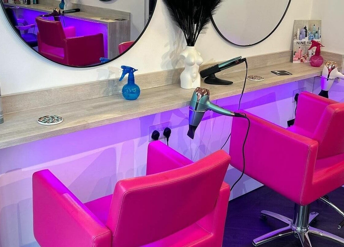 Vibrant pink salon chairs at The Look, Abingdon, England, GB, framed by modern mirrors.