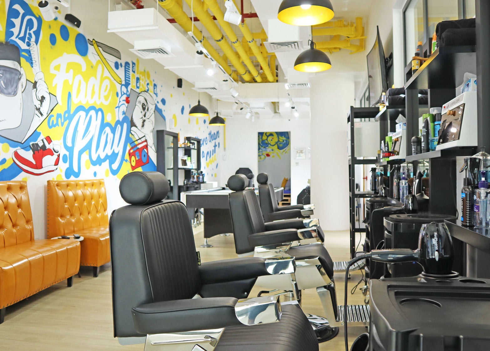 Modern salon interior at Fade & Play - Al Barsha, Dubai, Dubai, AE with colorful wall art and sleek barber chairs.
