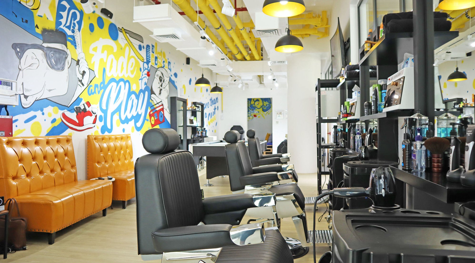 Modern salon interior at Fade & Play - Al Barsha, Dubai, Dubai, AE with colorful wall art and sleek barber chairs.