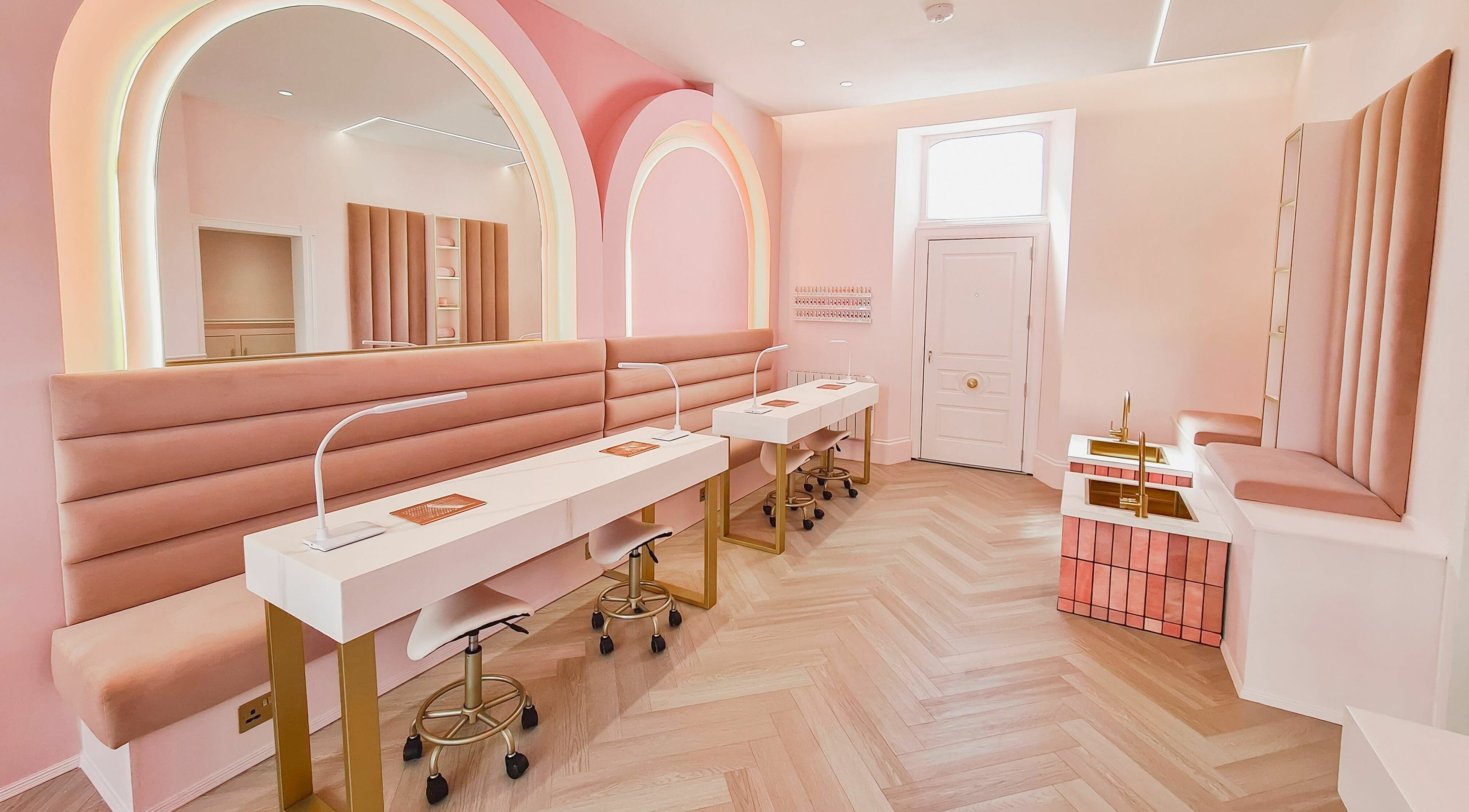 The Glow Up Nail Bar in Plymouth, England, GB showcases a chic and modern interior with soft pinks and gold accents.
