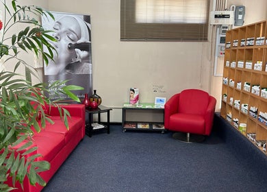 Inviting lounge area at Salon Elkana Health and Beauty, Vredendal, Western Cape, ZA, featuring red seating and product displays.