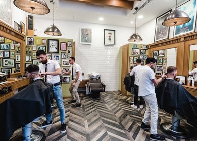 Stylish interior of Julian's Barbershop in Dubai, AE, with professionals at work in a lively atmosphere.
