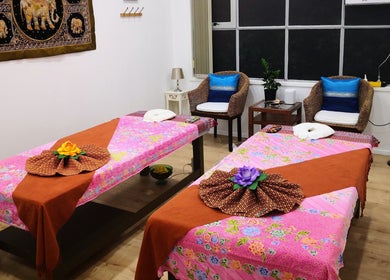 Relaxing massage room at Surin Thai Spa, Auckland, NZ, with vibrant floral decor and serene ambiance.