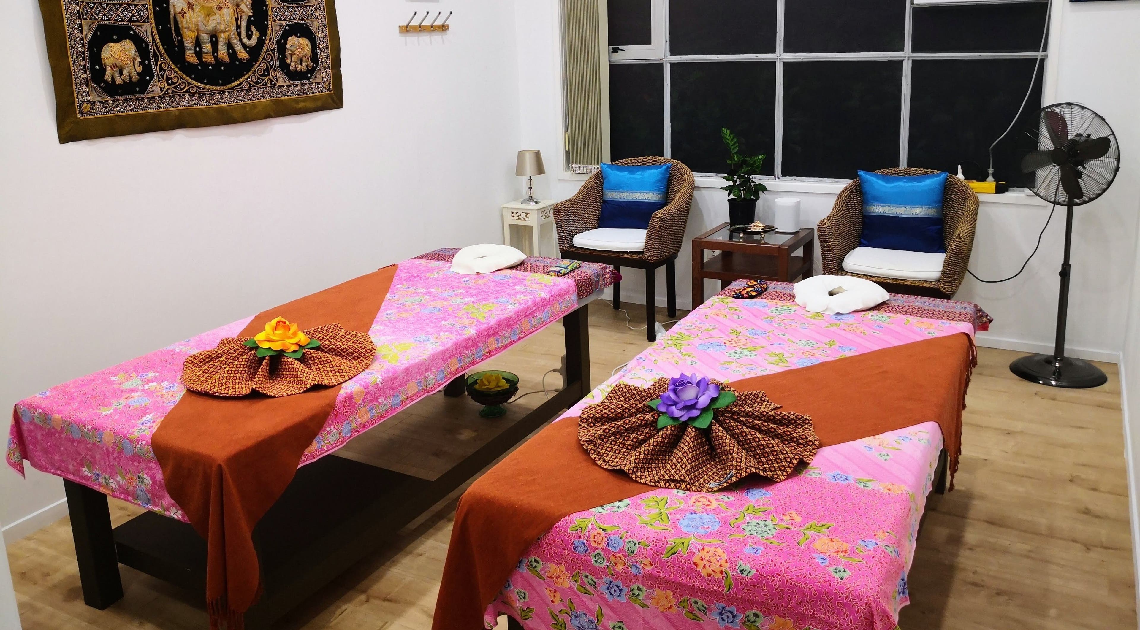 Relaxing massage room at Surin Thai Spa, Auckland, NZ, with vibrant floral decor and serene ambiance.