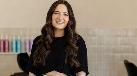 Smiling stylist at Harpar Hair, East Geelong, Victoria, AU with products in the background.