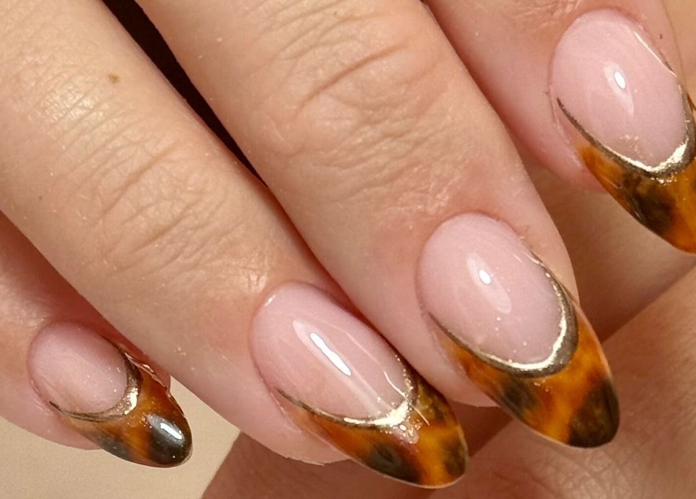 Intricate bronze nail art on manicured hands at Nails LCB in Havant, England, showcasing expert styling.