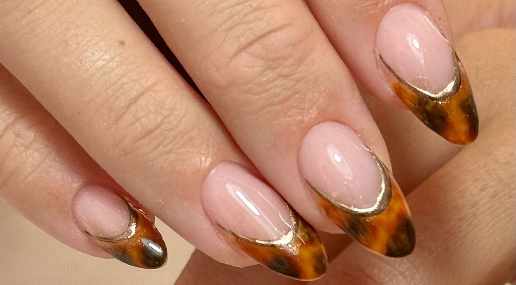 Intricate bronze nail art on manicured hands at Nails LCB in Havant, England, showcasing expert styling.