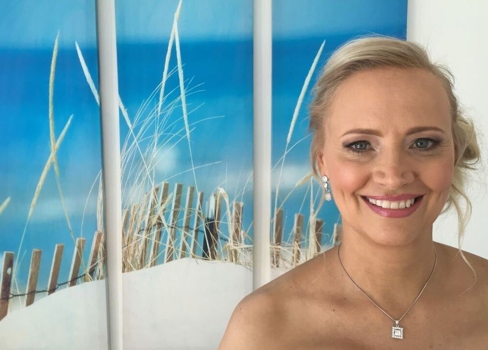 Smiling woman in Go Brown Durbanville Studio, Durbanville, Western Cape, ZA with beach art backdrop.