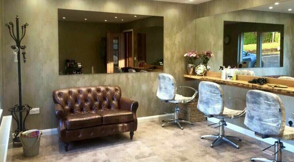 Elegant salon interior at Beautyme, Bathgate, Scotland, GB with a cozy brown leather sofa and styling chairs.