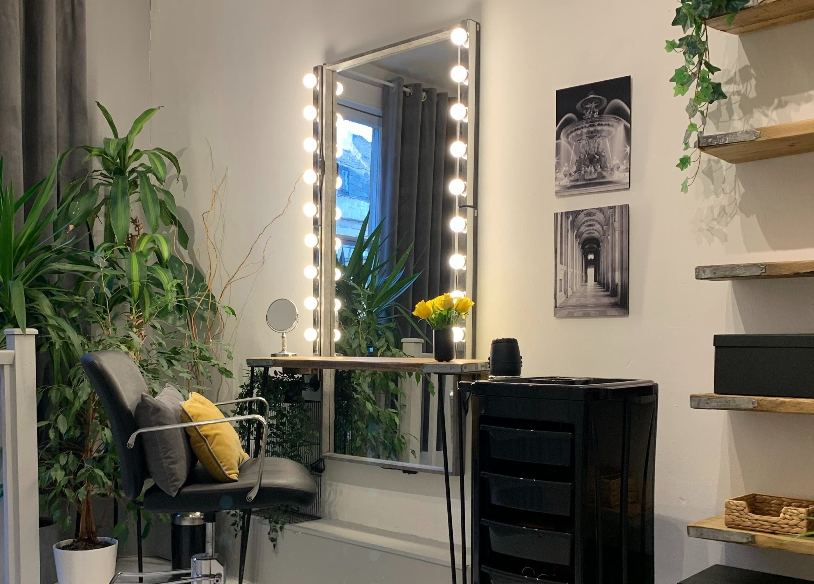 Elegant styling area at La Déesse Beauty Loft in Bath, England, GB with illuminated mirror and lush decor.