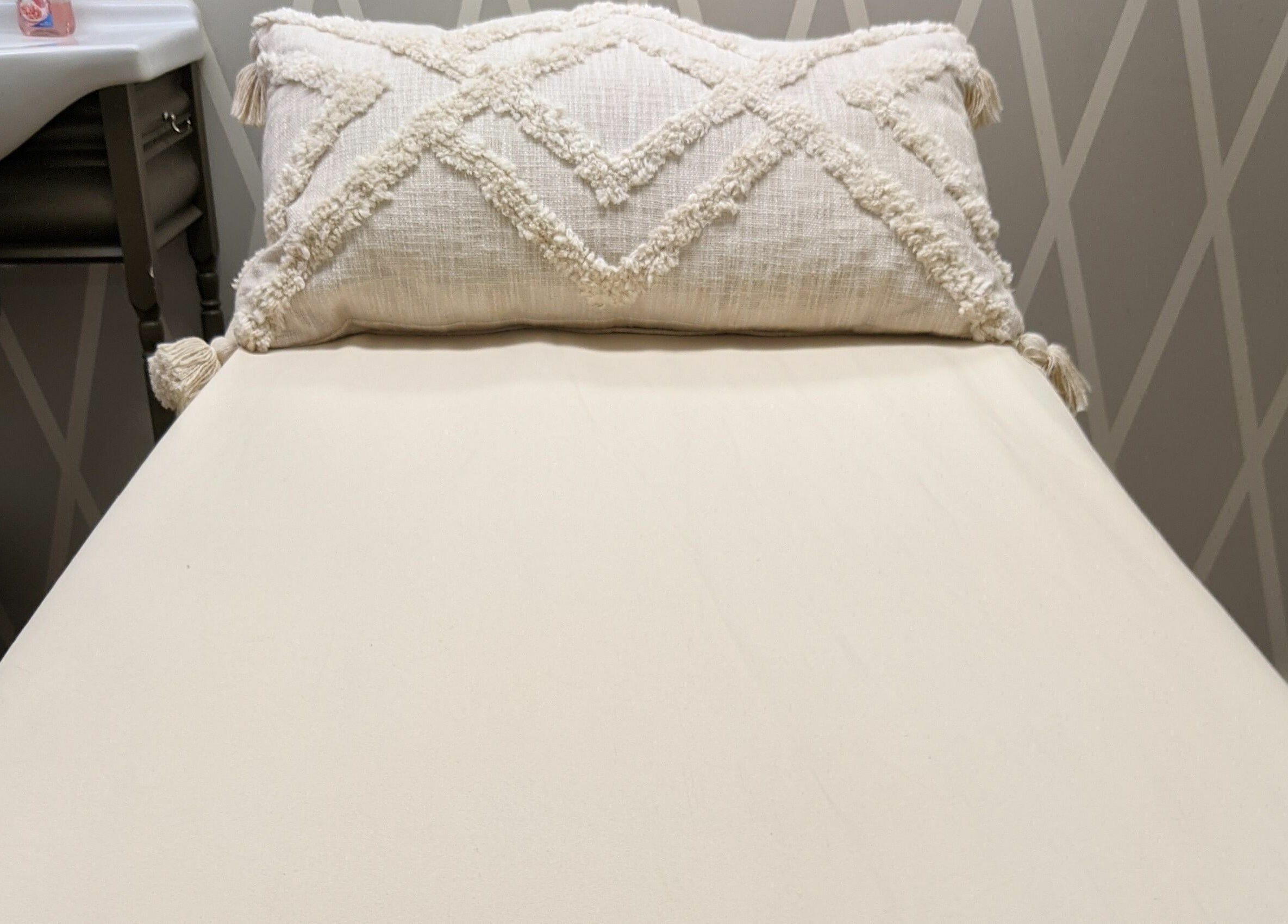 Comfortable spa bed at His & Hers Bare Beauty in Sarasota, FL with plush pillow for relaxation.