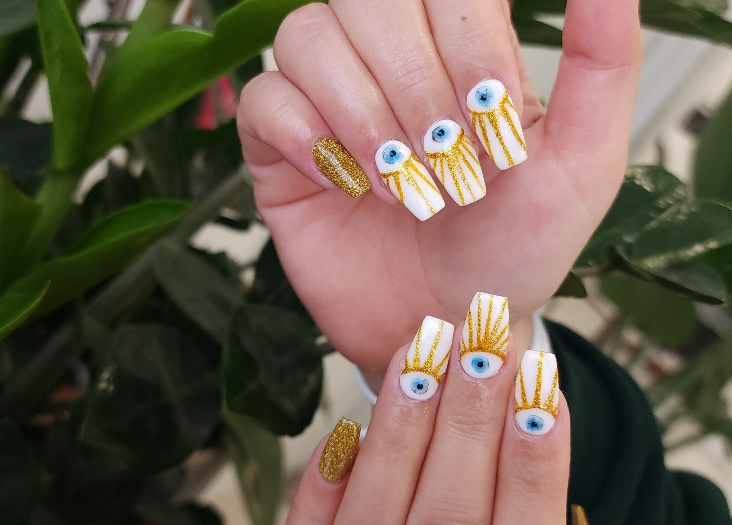 Intricate eye and gold glitter nail art at Serena Nails and Spa, Burlington, Massachusetts, US.