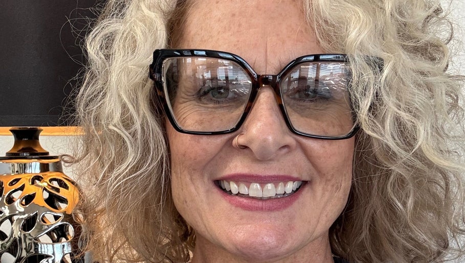 Blonde woman smiling with stylish glasses at Hair by Angelia Chandler Austin, Jonesboro, Arkansas, US.