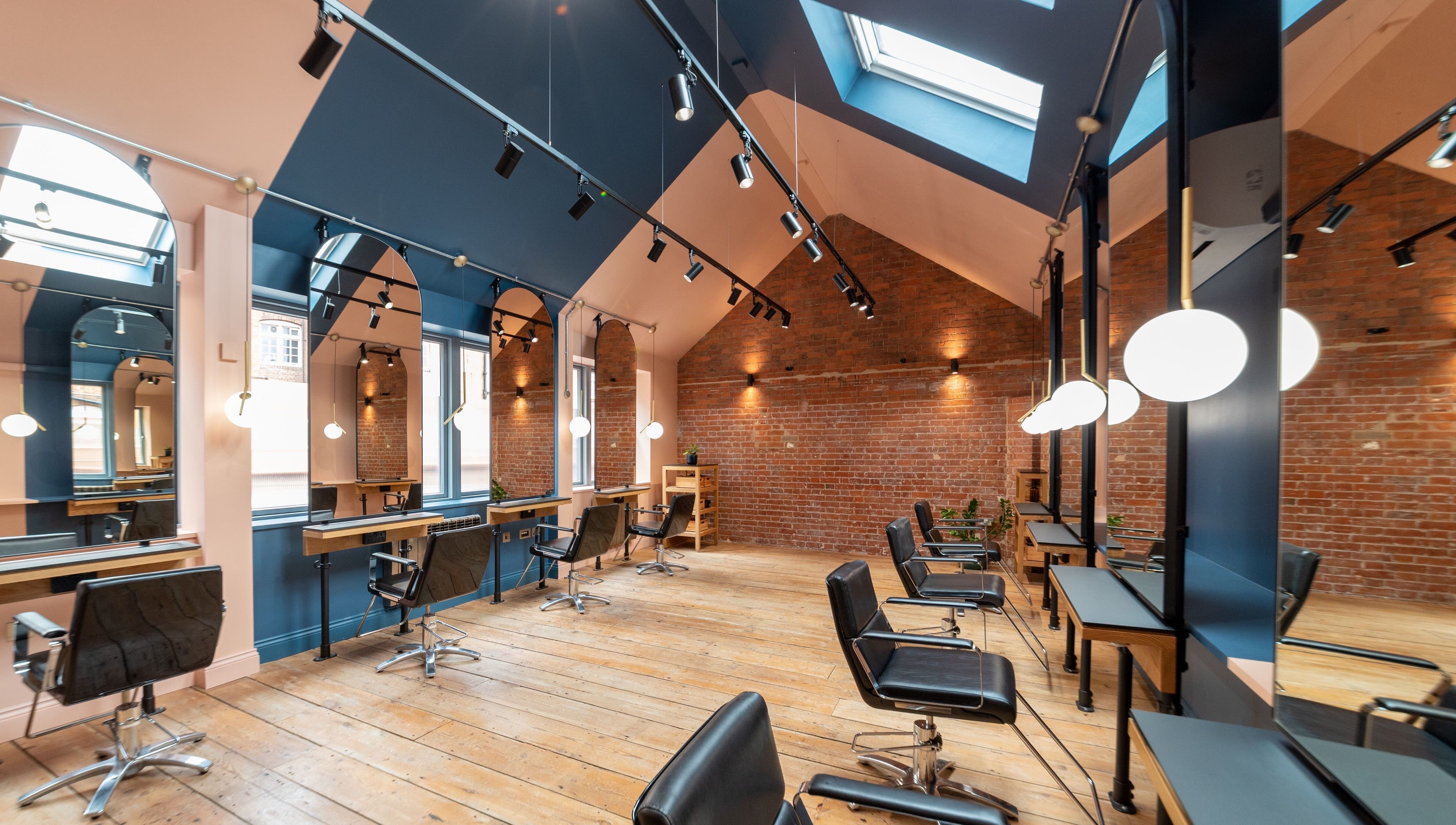 Modern salon at Bond, London, England, GB, featuring stylish chairs and reflective mirrors under skylights.