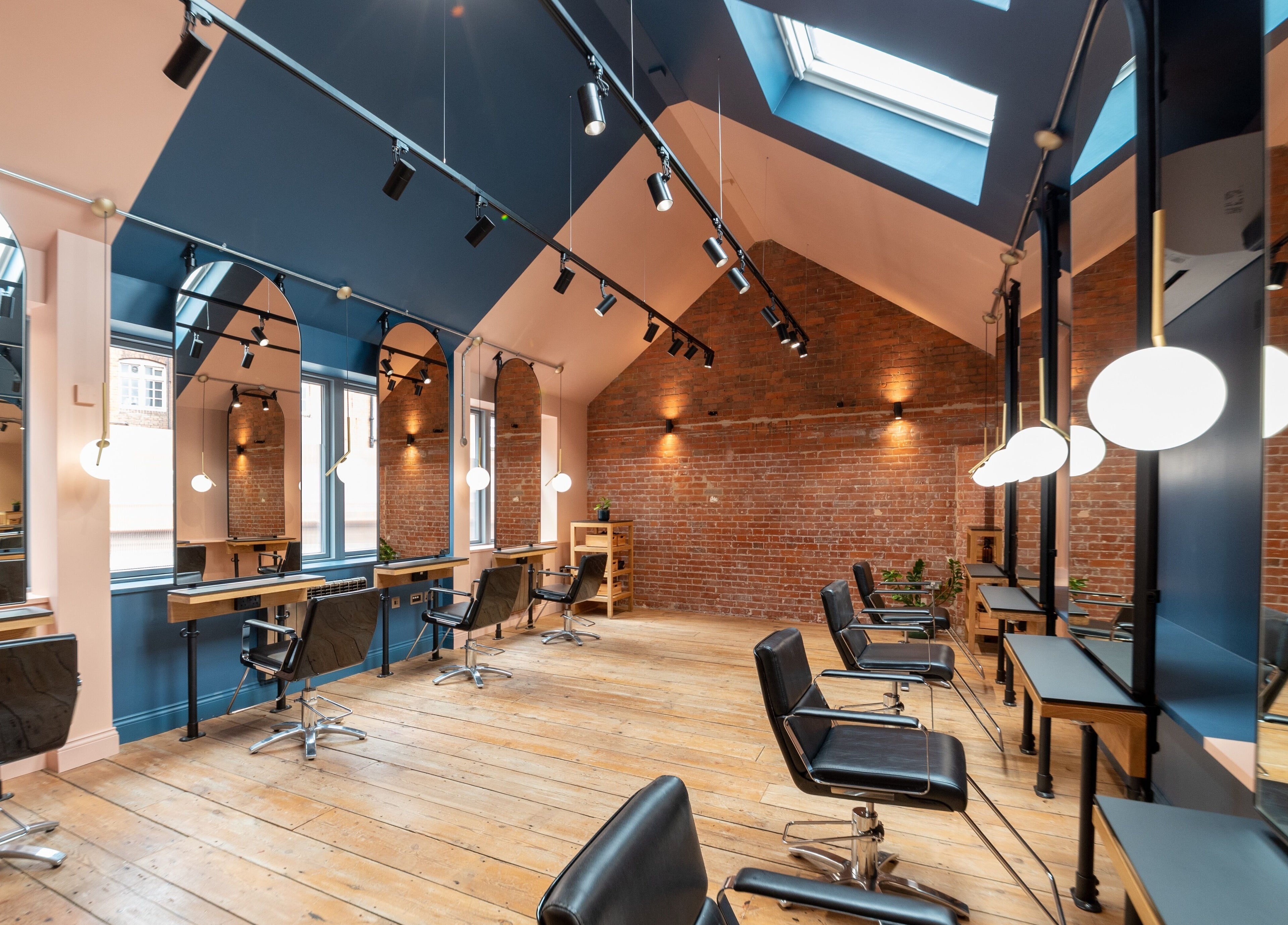 Modern salon at Bond, London, England, GB, featuring stylish chairs and reflective mirrors under skylights.