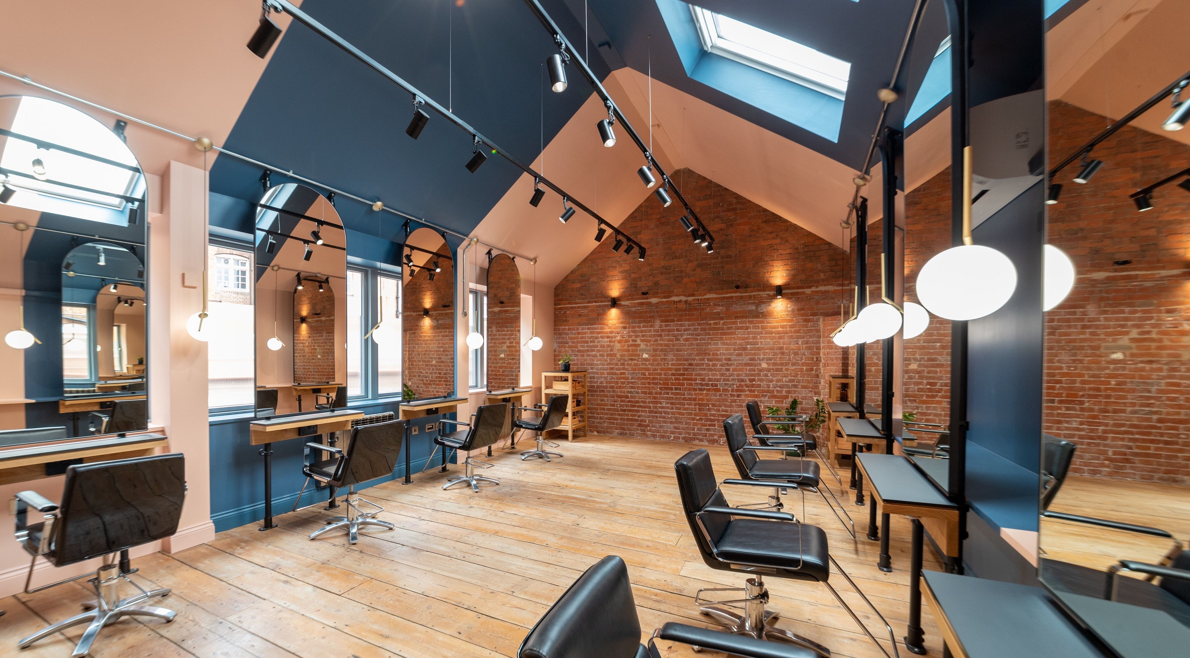 Modern salon at Bond, London, England, GB, featuring stylish chairs and reflective mirrors under skylights.